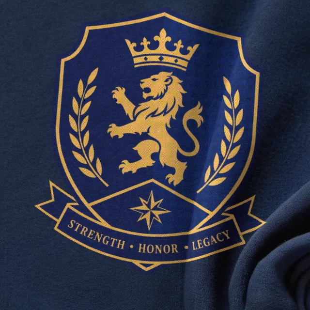 Close-up of a navy T-shirt printed with a gold crest, a lion and laurels, in diamond halftone dots, the shirt showing through the shield.